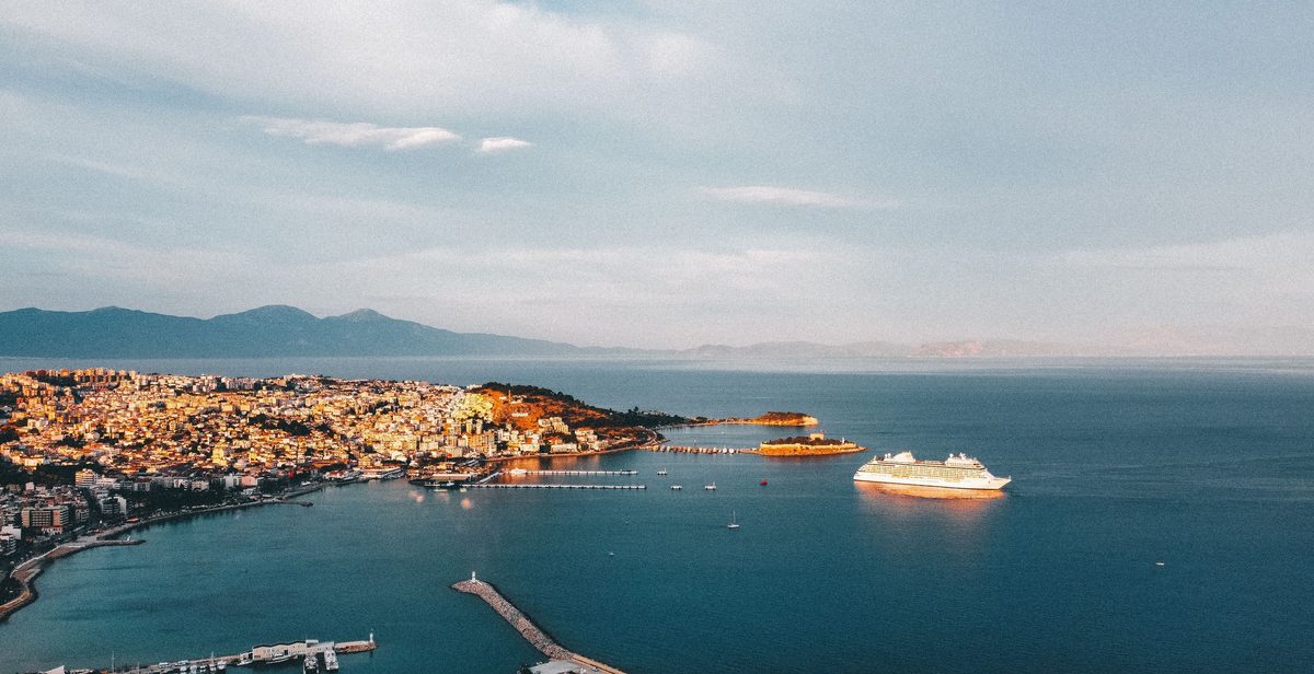 Kuşadası bay from the air at dusk: the marina breakwater, Pigeon Island and a cruise ship lying off the town